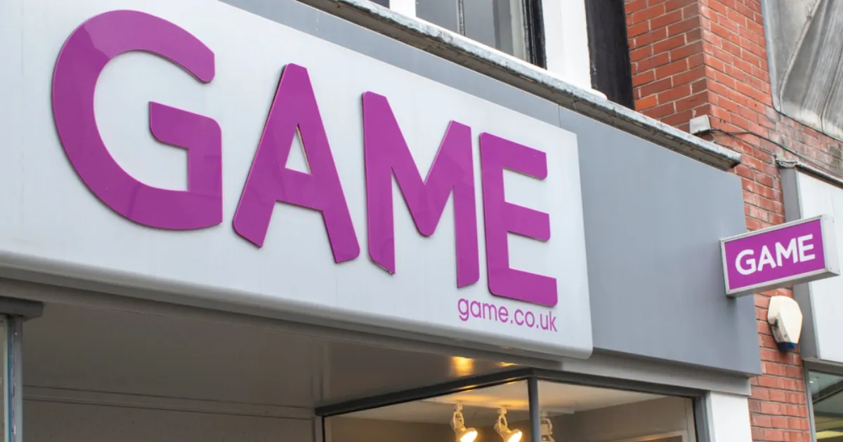 Close-up shot of a GAME store sign featuring the purple 'GAME' logo with 'game.co.uk' beneath it, mounted on a grey storefront.