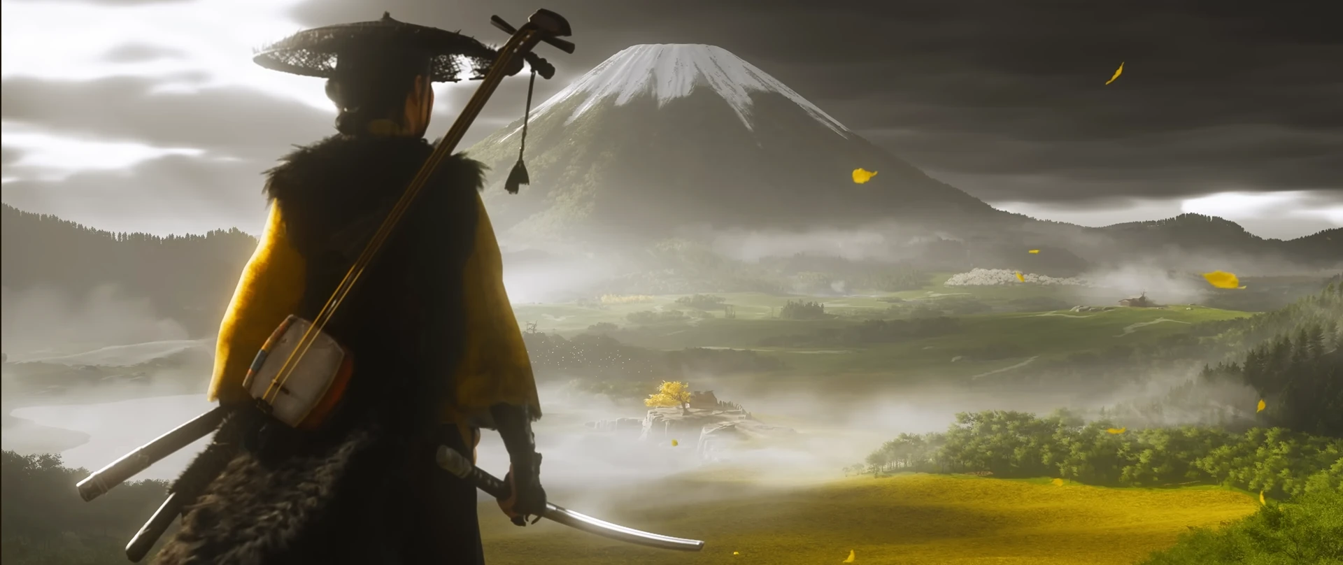 Atsu, seen from behind, stands with a katana at her hip and a shamisen strapped to her back, gazing at a snow-capped Mount Yōtei under a dramatic sky with scattered yellow leaves. The landscape below is a vibrant mix of green and golden fields, dotted with trees and a distant structure.