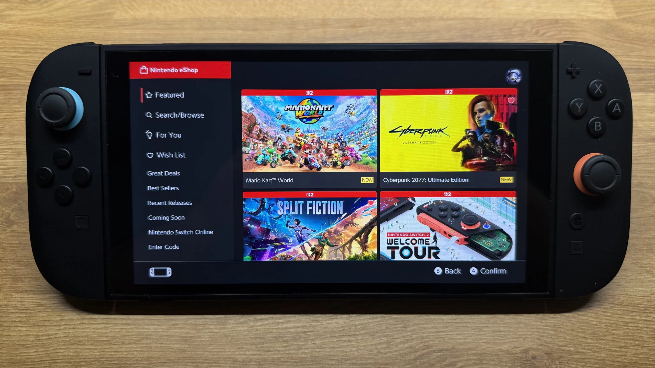 A close-up shot of the Nintendo Switch 2 displaying its eShop interface with "Mario Kart World," "Cyberpunk 2077: Ultimate Edition," "Split Fiction," and "Welcome Tour" visible.